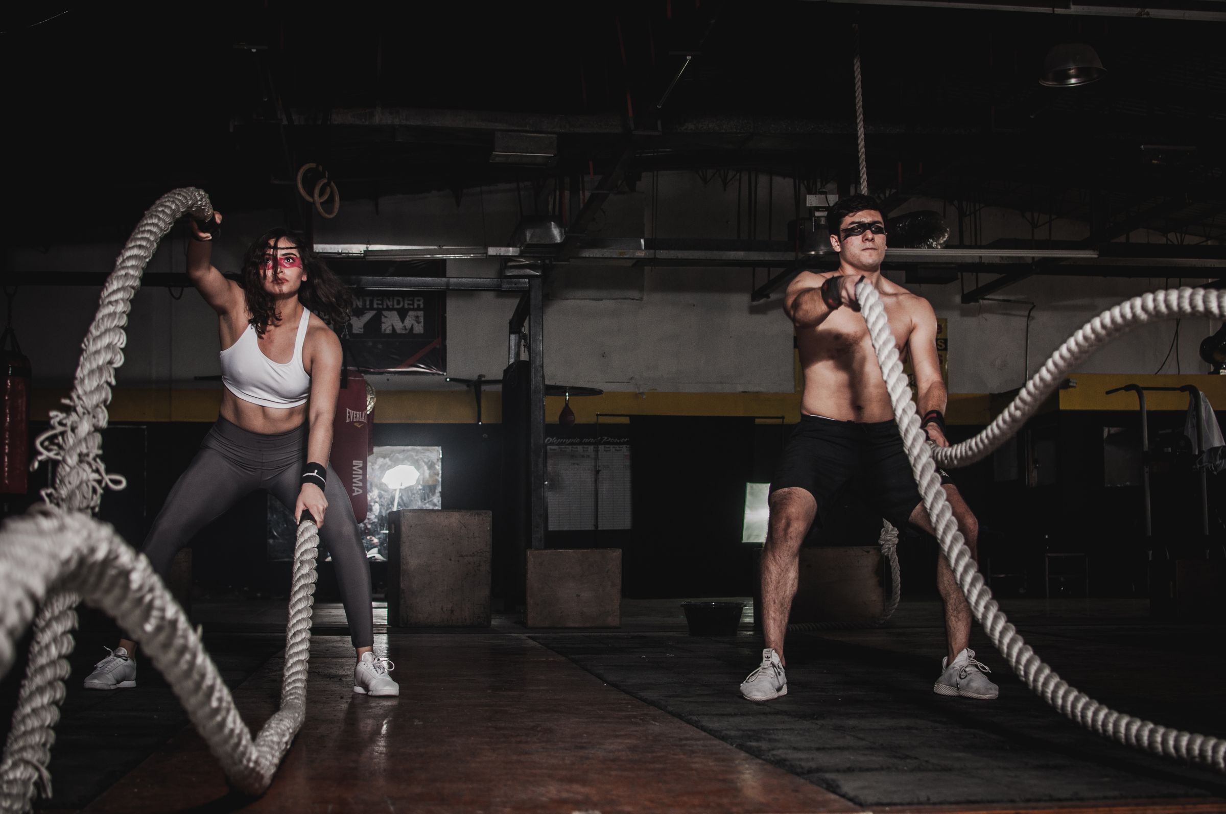Athletes training battle ropes in a dark gym